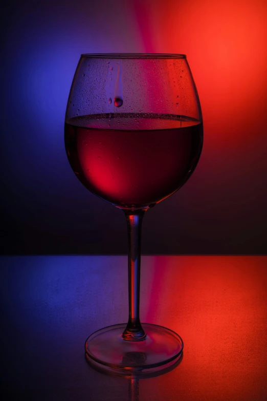 a wine glass with red wine in it on a counter