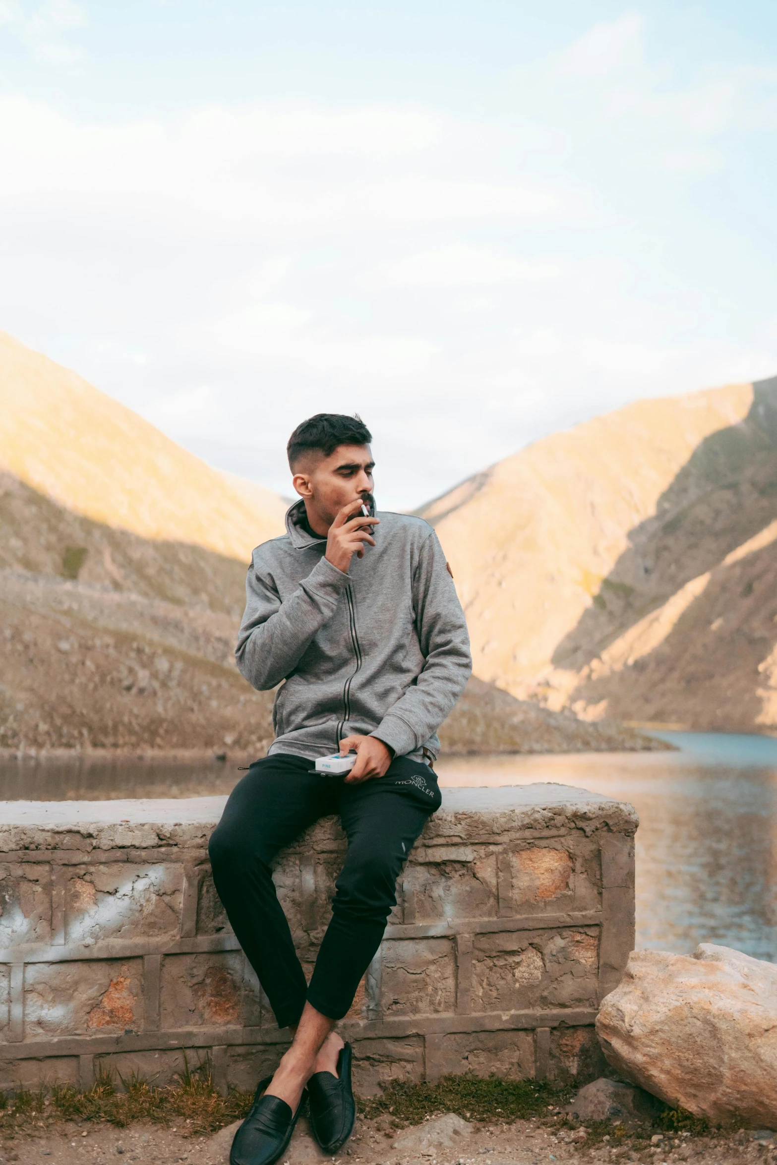 a man in grey sweater sitting on ledge