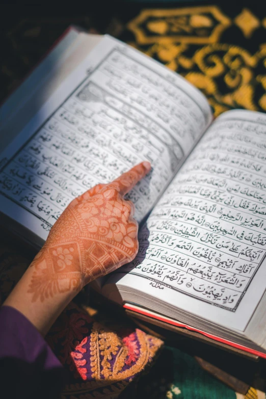 an arabic hand rests on top of a page of the holy book