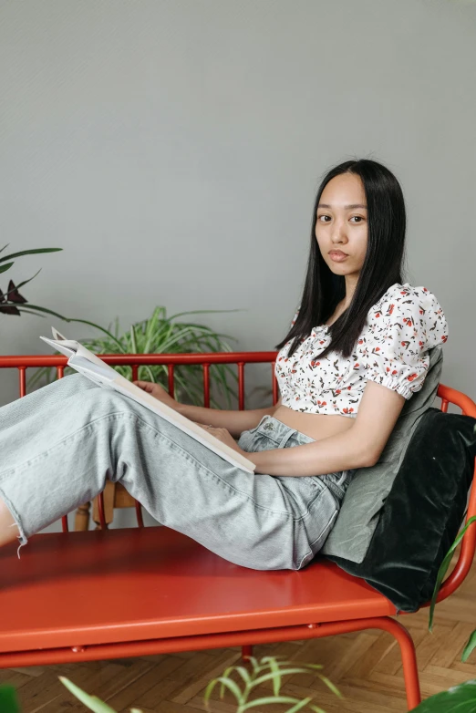 a girl sitting on a small bench and reading