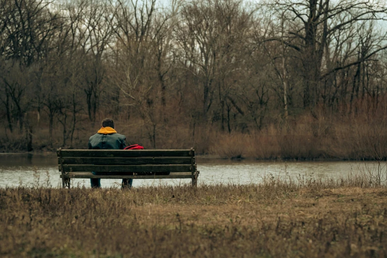 two people sitting on a bench by the lake