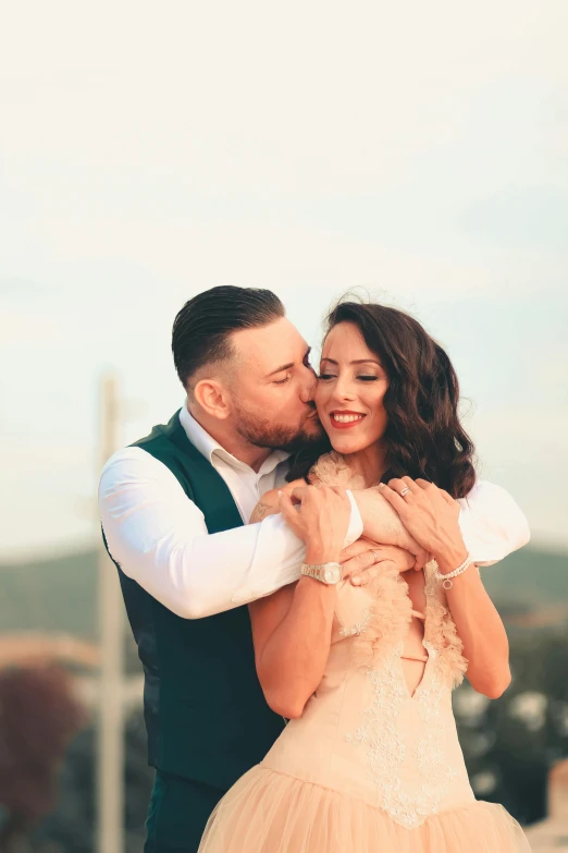 man in vest and skirt hugging woman, who is wearing pink dress