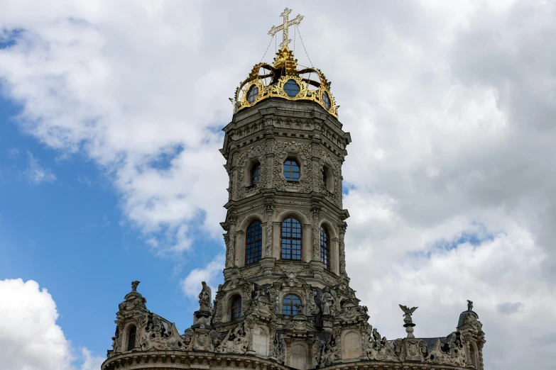 large clock tower with golden details in front of cloudy blue sky