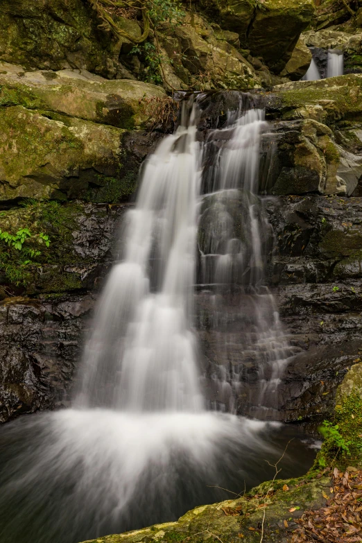 the waterfall is surrounded by moss and rocks