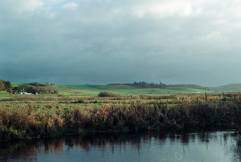 a small stream flowing through a grass covered countryside