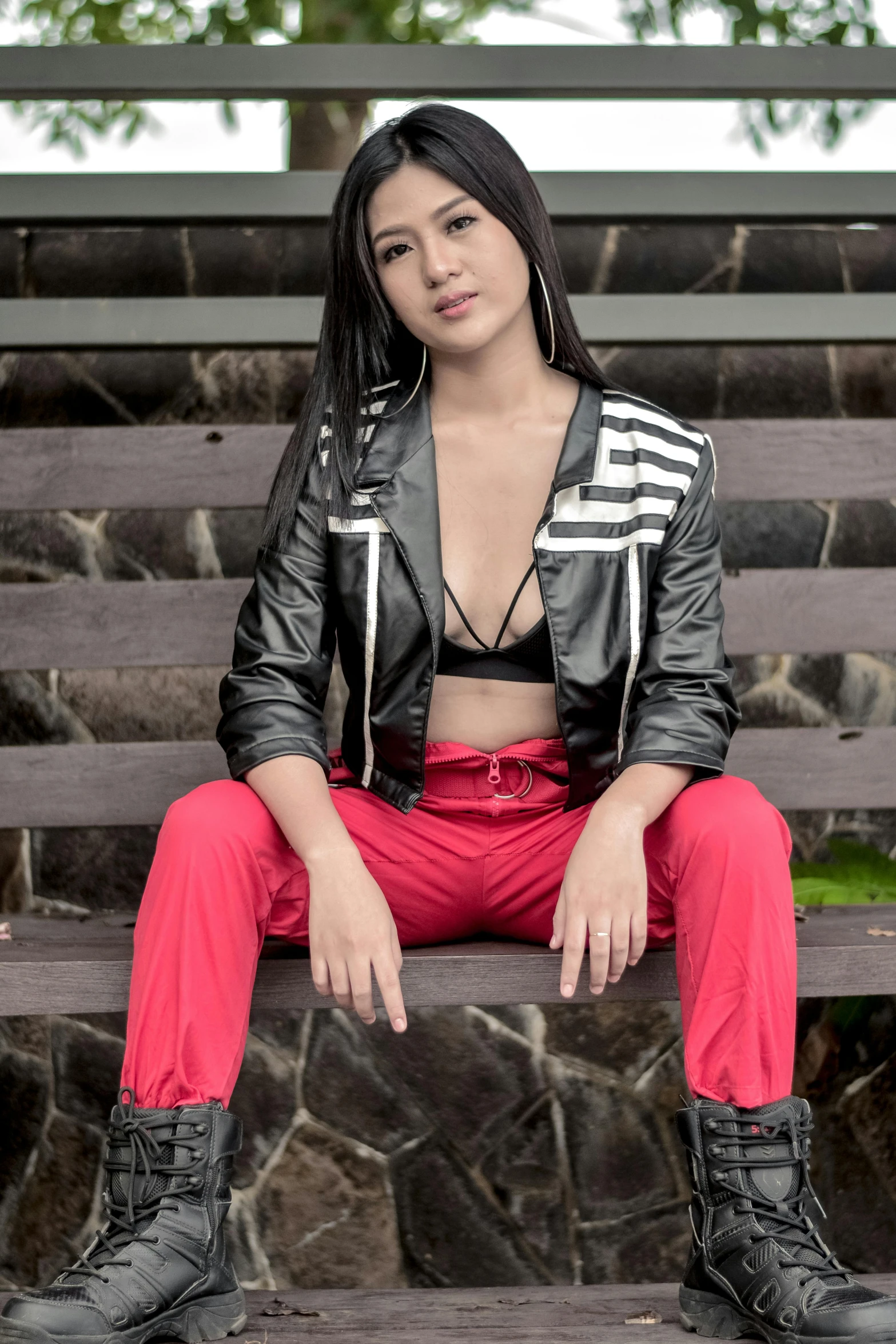 a woman in red pants and a jacket is sitting on a bench