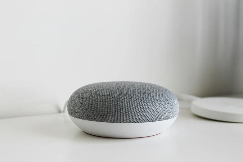 a google home mini on top of white countertop