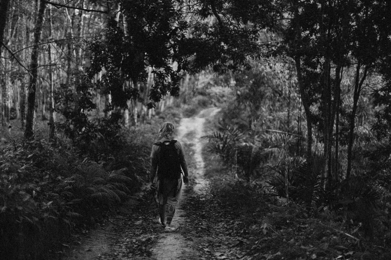 a man walking down a dirt trail through a forest