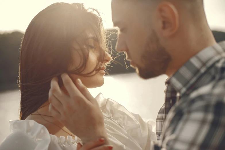 man and woman looking at each other next to a lake