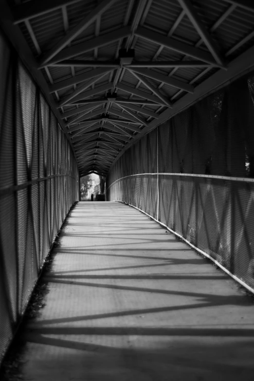 a long walkway on a bridge with shadows on it