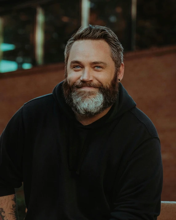 a bearded man in a black shirt is looking at the camera