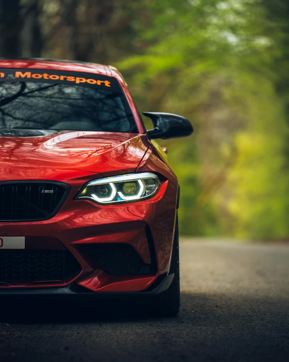 the front end of a red car with a company logo on it