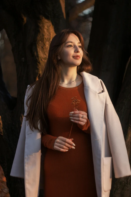 young woman in brown dress holding a brown flower