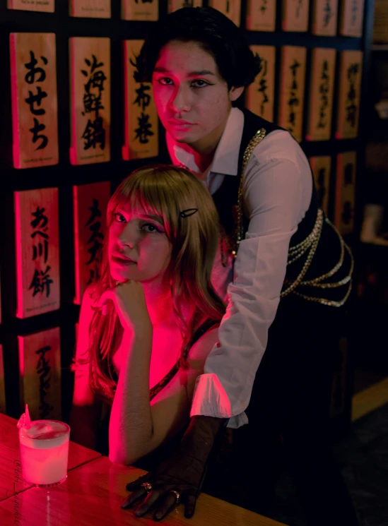 a couple posing for a po at a bar with pink light