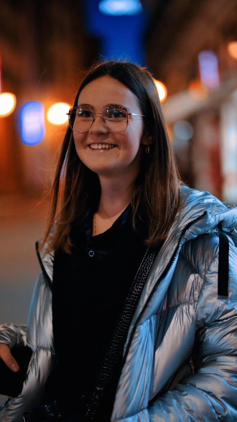 young woman in glasses and a jacket looks off to the side
