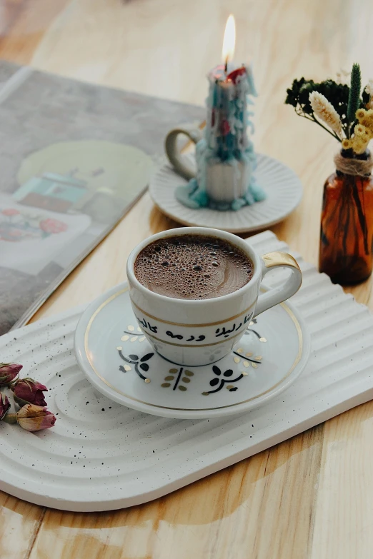 a cup of  chocolate sits on a plate with a teapot