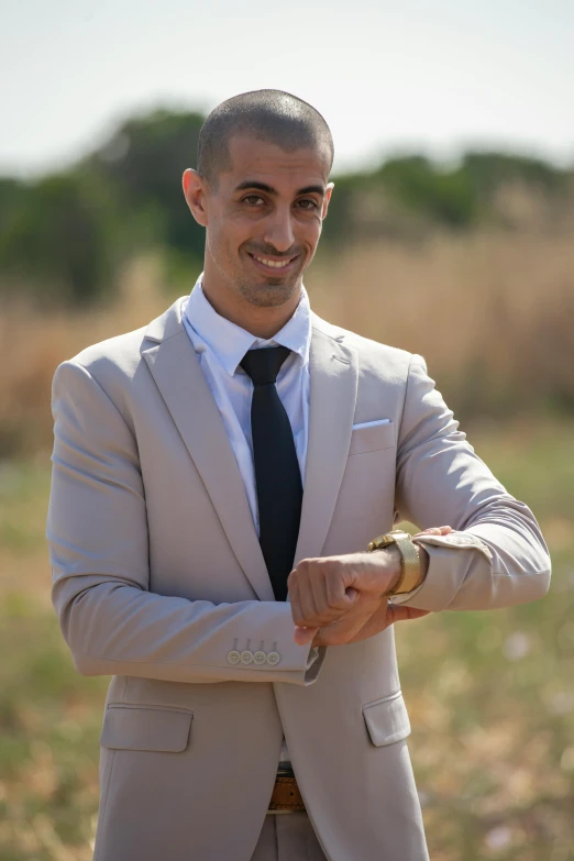 a man in a tan suit and black tie posing for the camera