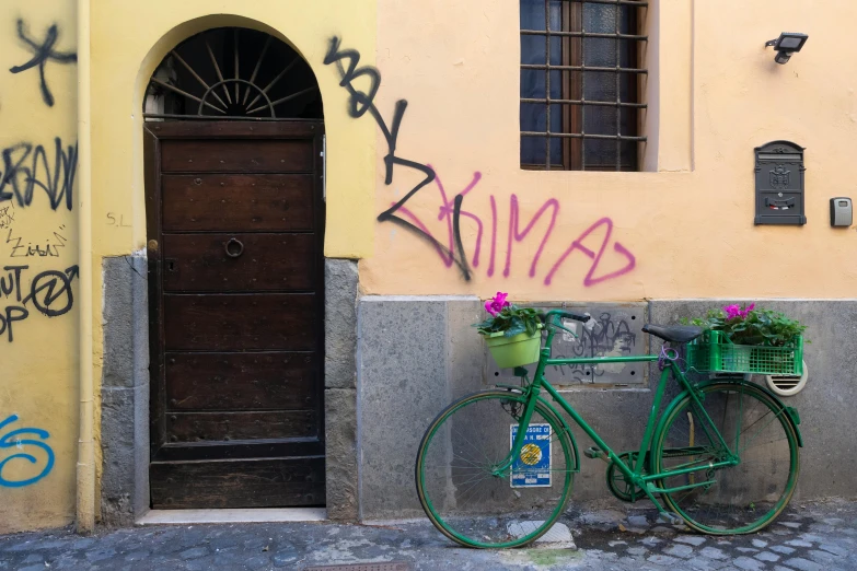 a green bicycle is  to the side of a yellow building