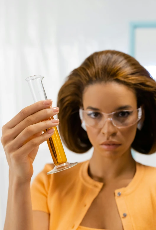 a woman wearing glasses and holding a test tube in her hand