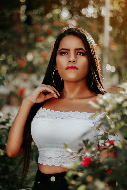 the young woman is posing near many bushes