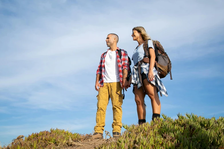 two people standing on a hill under a blue sky