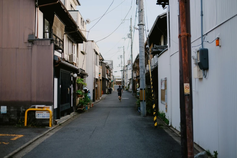 people walk down an alley lined with old buildings