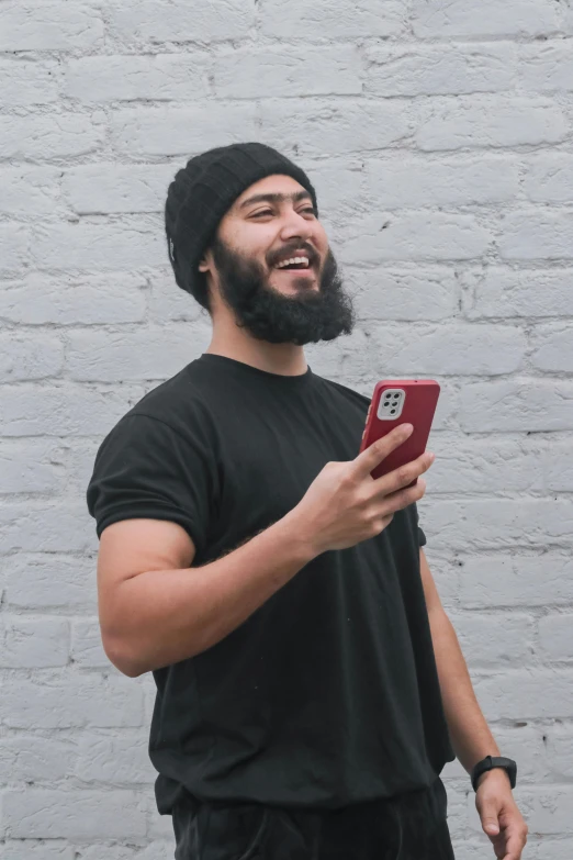 man with beard in front of white brick wall and smiling