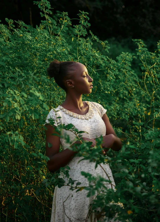 woman in white dress standing in front of bushes