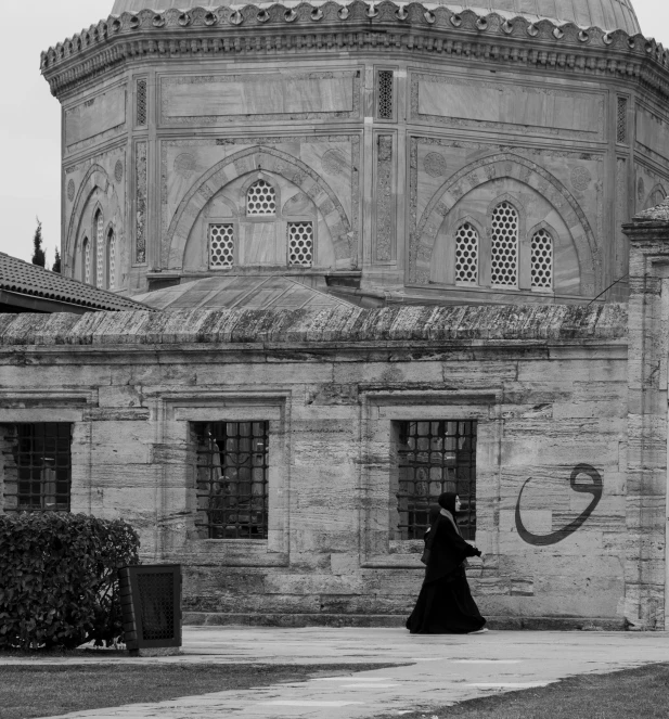 black and white image of a person walking by a building