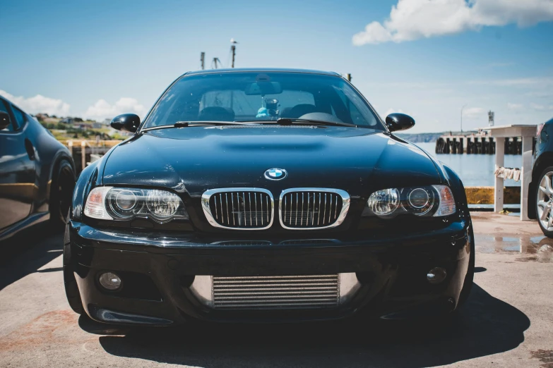 the front view of a black bmw parked next to another black bmw