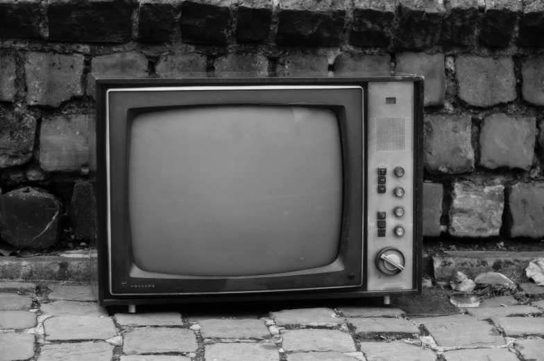 an old television is in front of a brick wall