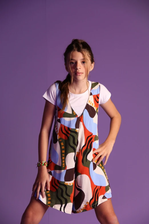 a girl is standing on purple background wearing an abstract print