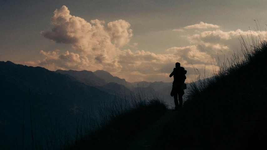 a person walking in a valley under a cloudy sky