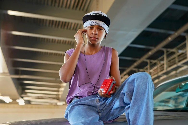 the  is sitting on top of a car talking on his phone