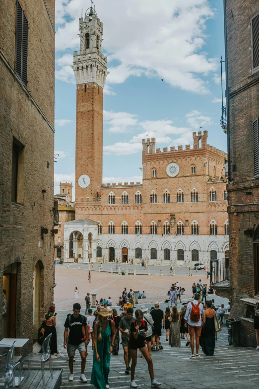 many people walking up and down the steps to a tall building with a clock tower