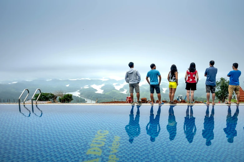 three people standing at the edge of an outdoor pool