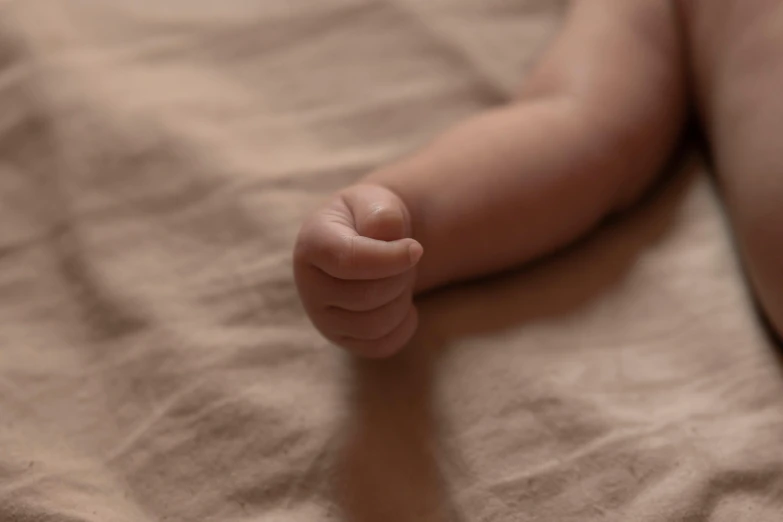 a baby's foot rests on a bed in soft pink colors