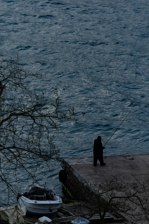 there is a man walking along the edge of a pier fishing