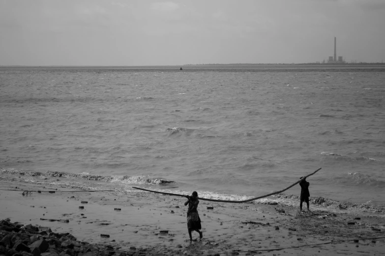 two people stand in the ocean with a large boat behind them