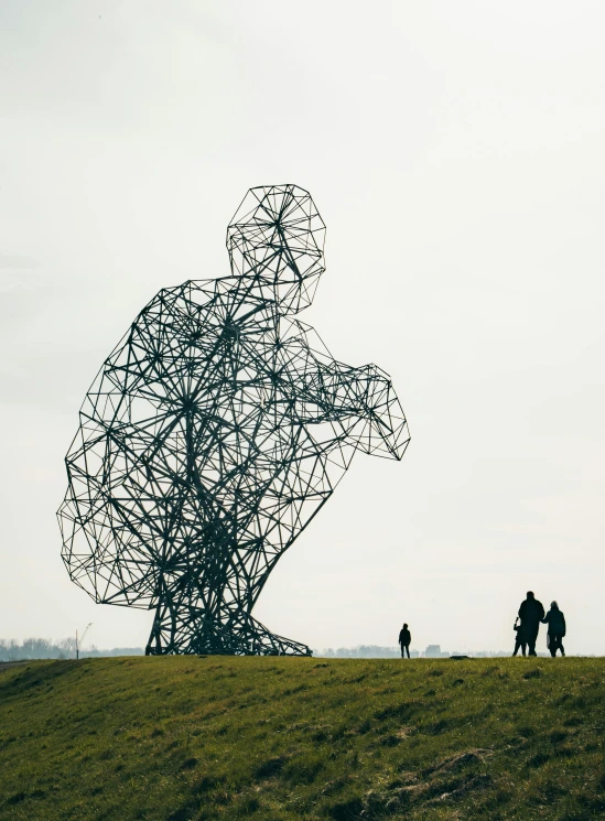 some people are walking by a sculpture on top of a hill
