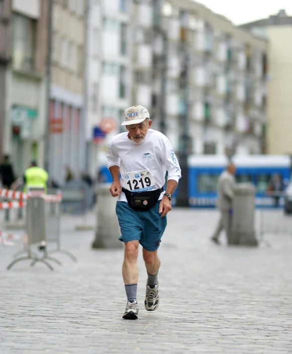 a man wearing white shirt and blue shorts running down street