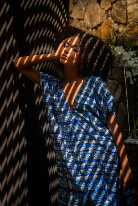 a black woman leaning against a fence with her hands near her face