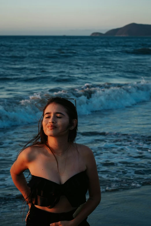 the girl is standing by the waves looking to the side