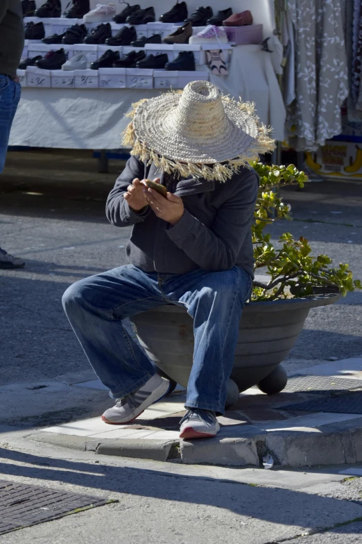 a man sitting down while wearing a large hat