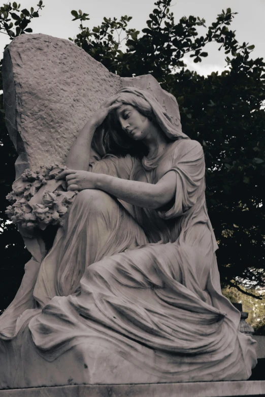 a statue in front of a tree that is taller than the size of a rock