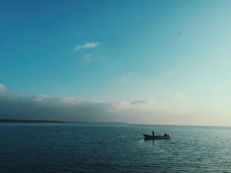 a small boat floating in the middle of an ocean