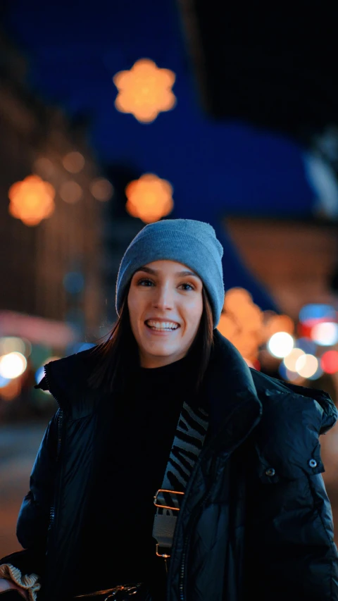 a person standing outside and smiling while wearing winter clothes