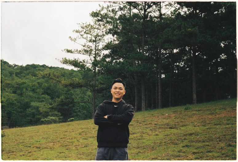 a man standing in the grass near some trees