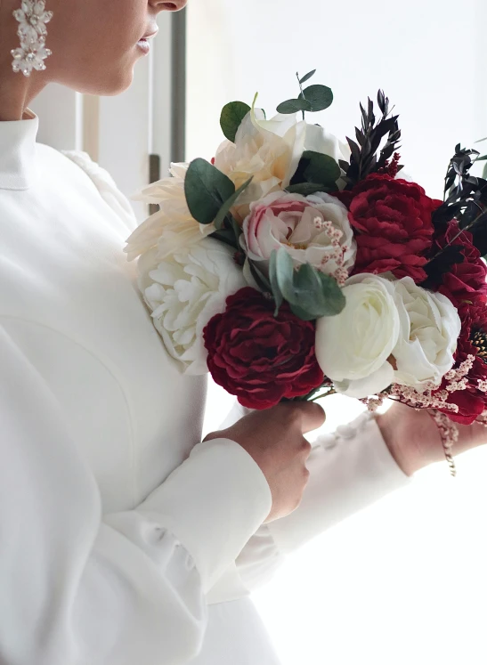 the bride wears a red and white bouquet