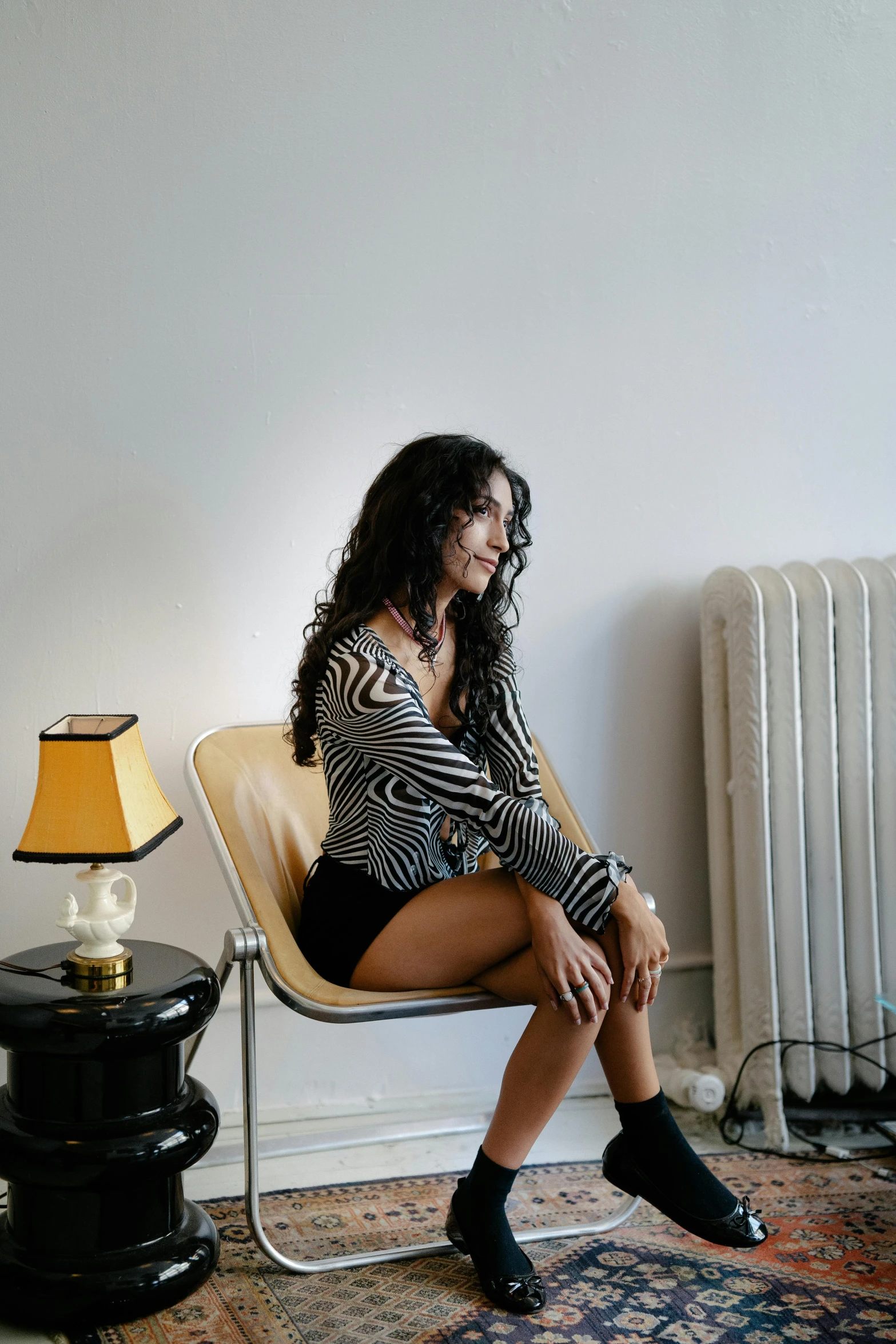 a woman in striped shirt sitting in chair next to lamp